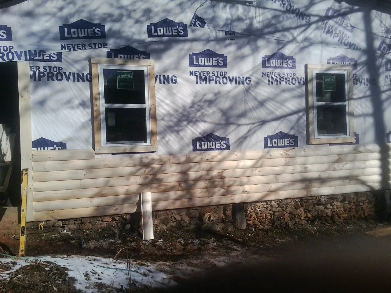 House wrap and new log siding going up on an exterior wall in Leominster