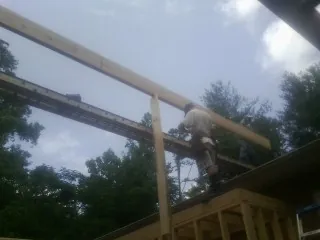 Carpenter setting a ridge beam over a new addition frame — Ice Dam Removal by Roofing Brothers in Leominster