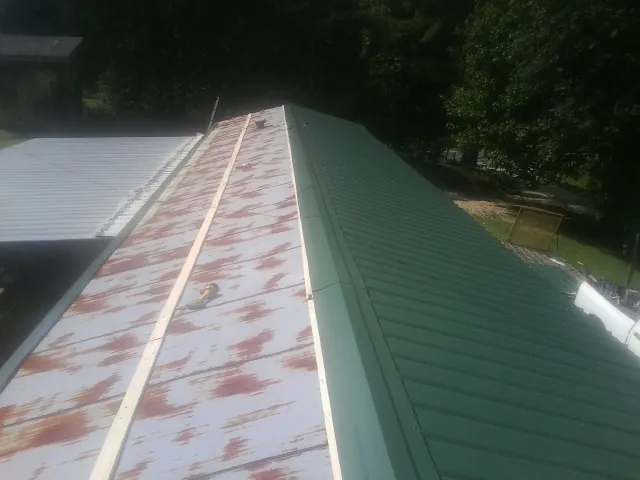 Old rusted panels beside newly installed green metal roofing — Wind Damage Roof Repair by Roofing Brothers in Leominster