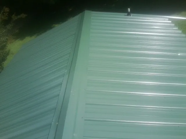 New green metal panels meeting at the ridge of a roof — Flat Roof Repair work by our crew in Leominster