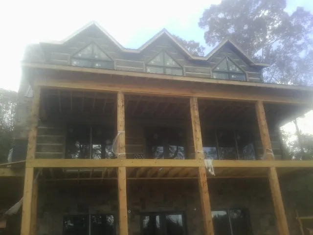 Dormers and porch framing on a large log home under construction — Roof Coating work by our crew in Leominster