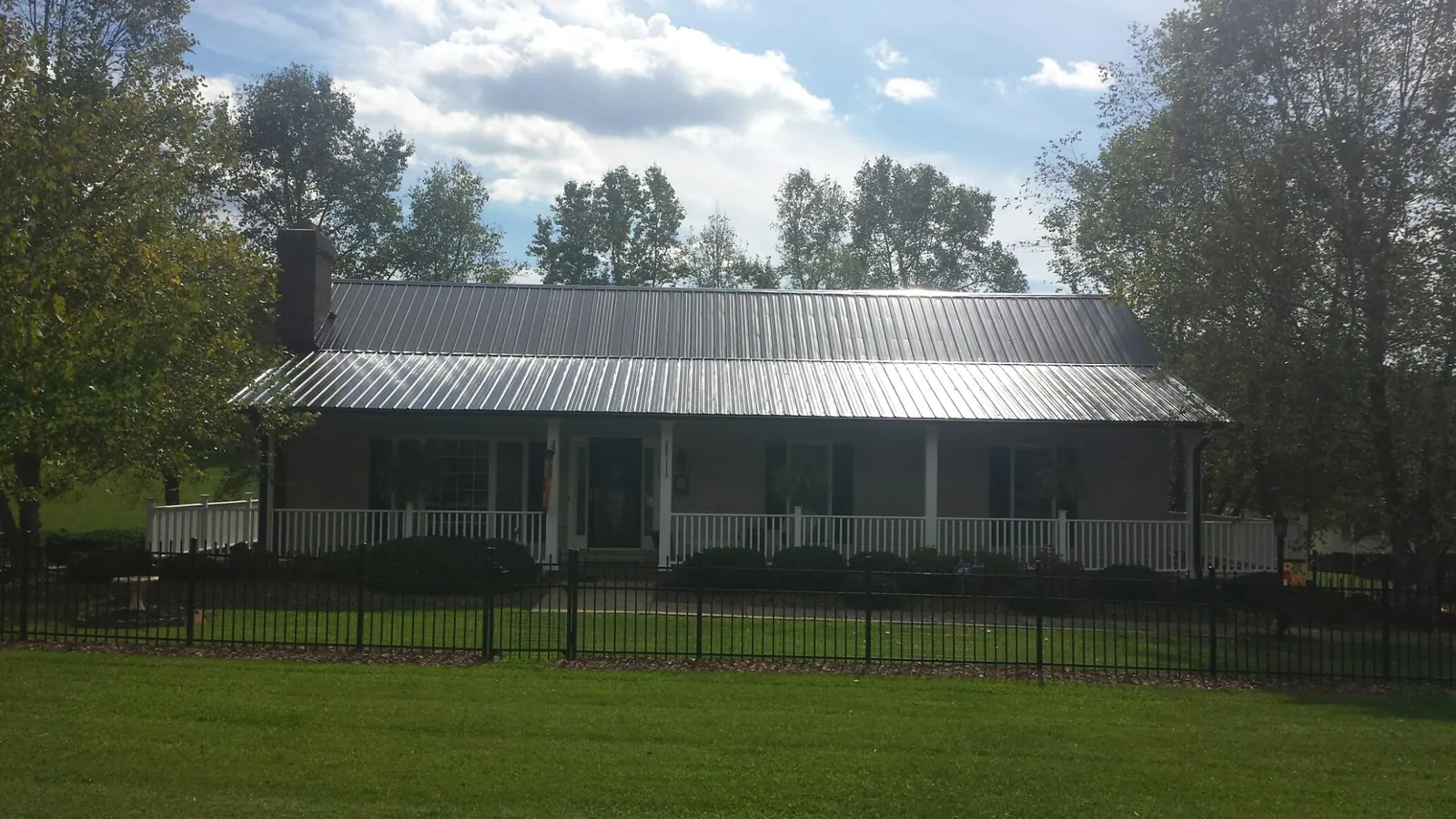 Gray metal roof on a brick ranch with a full width front porch — Gutter Guard Installation work by our crew in Leominster