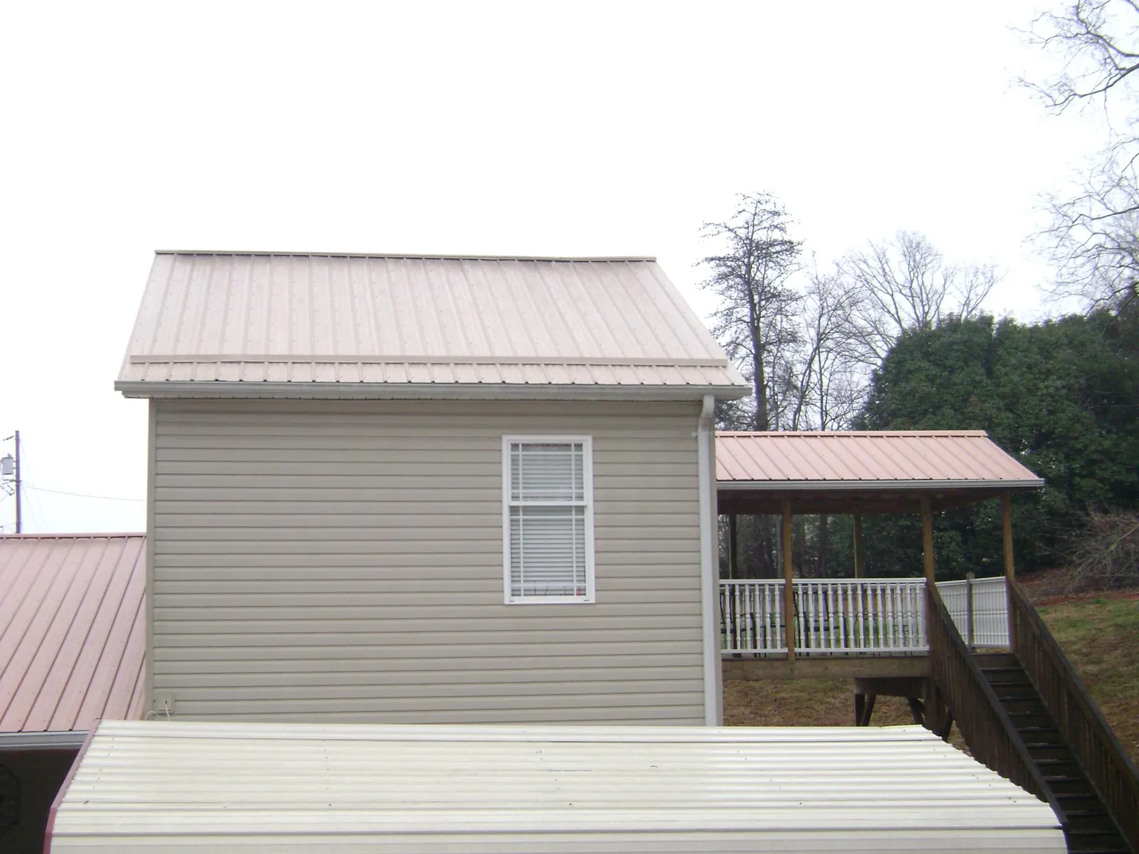 Tan metal roofs on a two story addition and attached porch, from a Roof Replacement job in Leominster