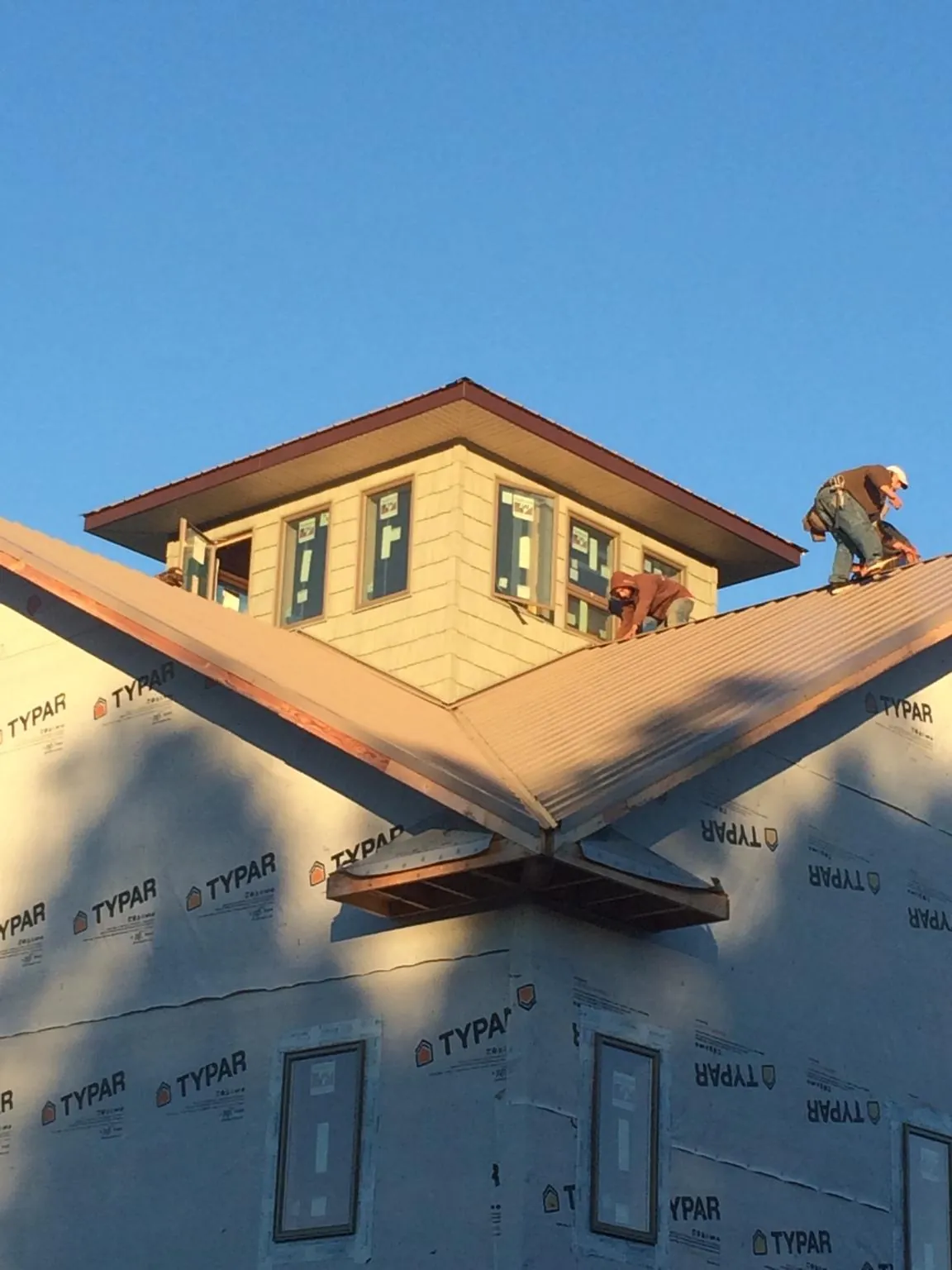 Roofers working around a rooftop cupola on a new metal roof at sunset — Roof Waterproofing in Leominster by Roofing Brothers